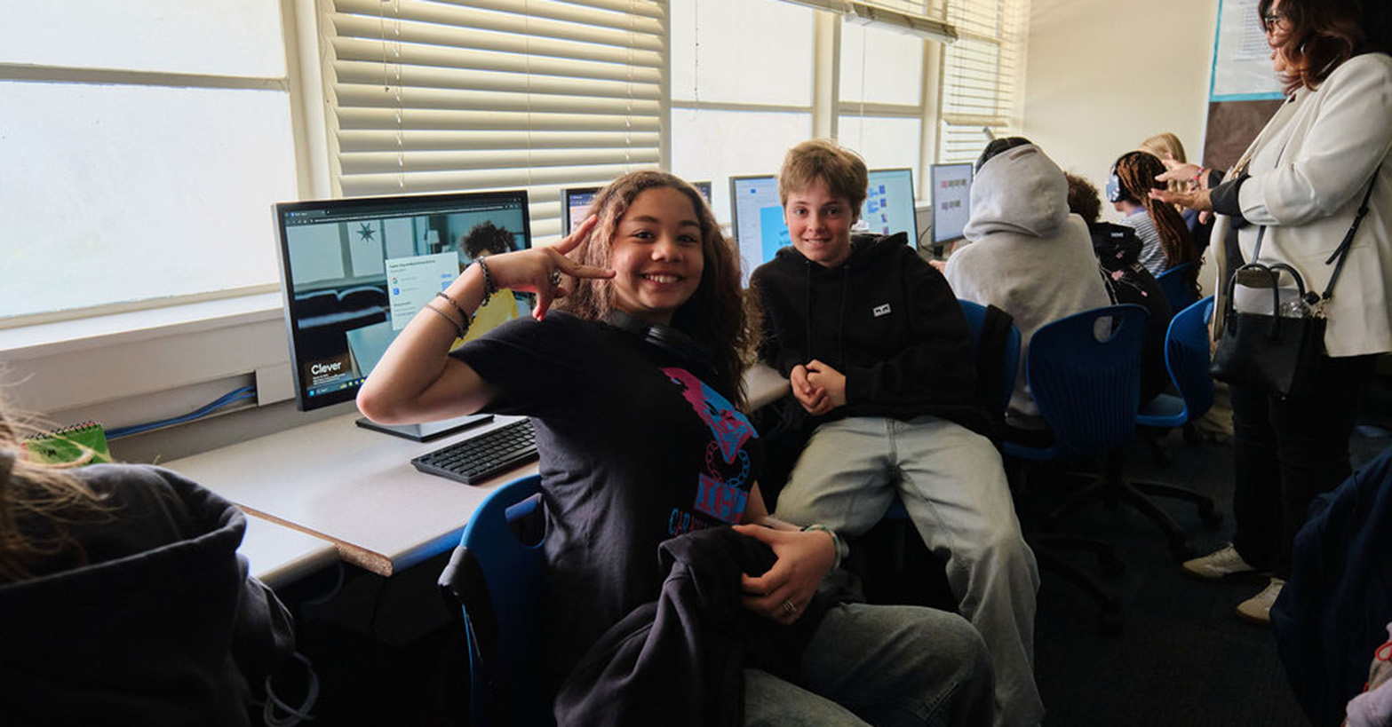 Girl and boy pose in front of computer