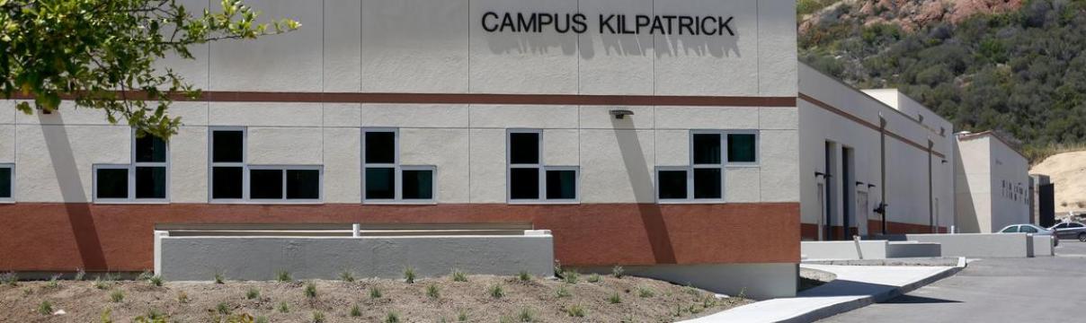 Tan building with the words Campus Kilpatrick. Mountains are in the background.